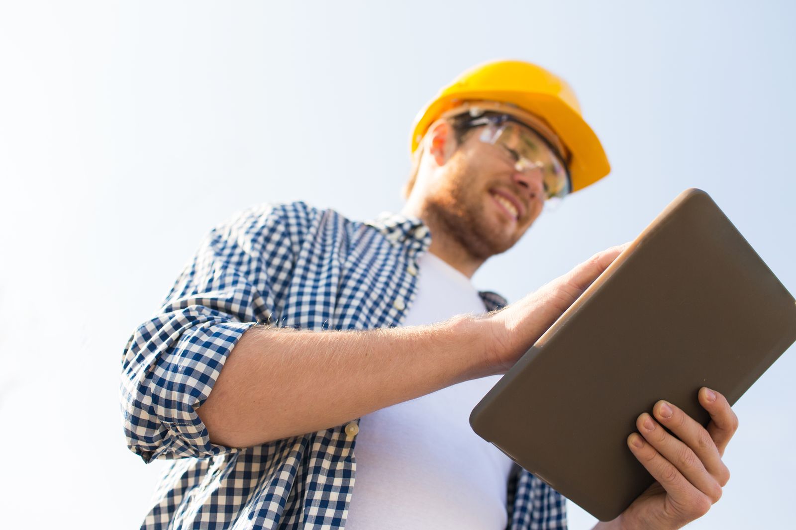 Contractor in a hard hat reading a tablet on a job site